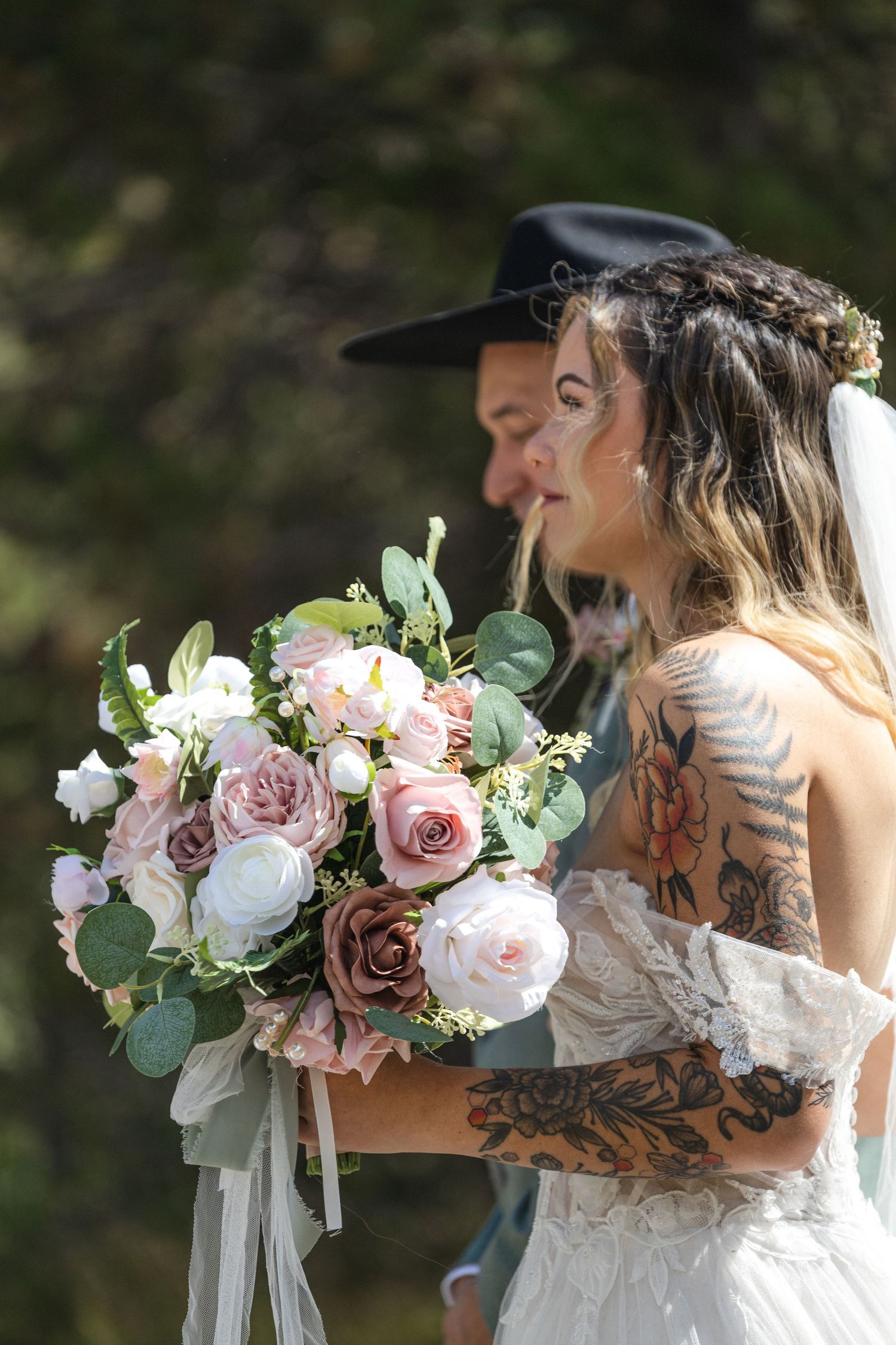 Elegant bridal bouquet with pink and white roses and eucalyptus held at an outdoor wedding ceremony.
