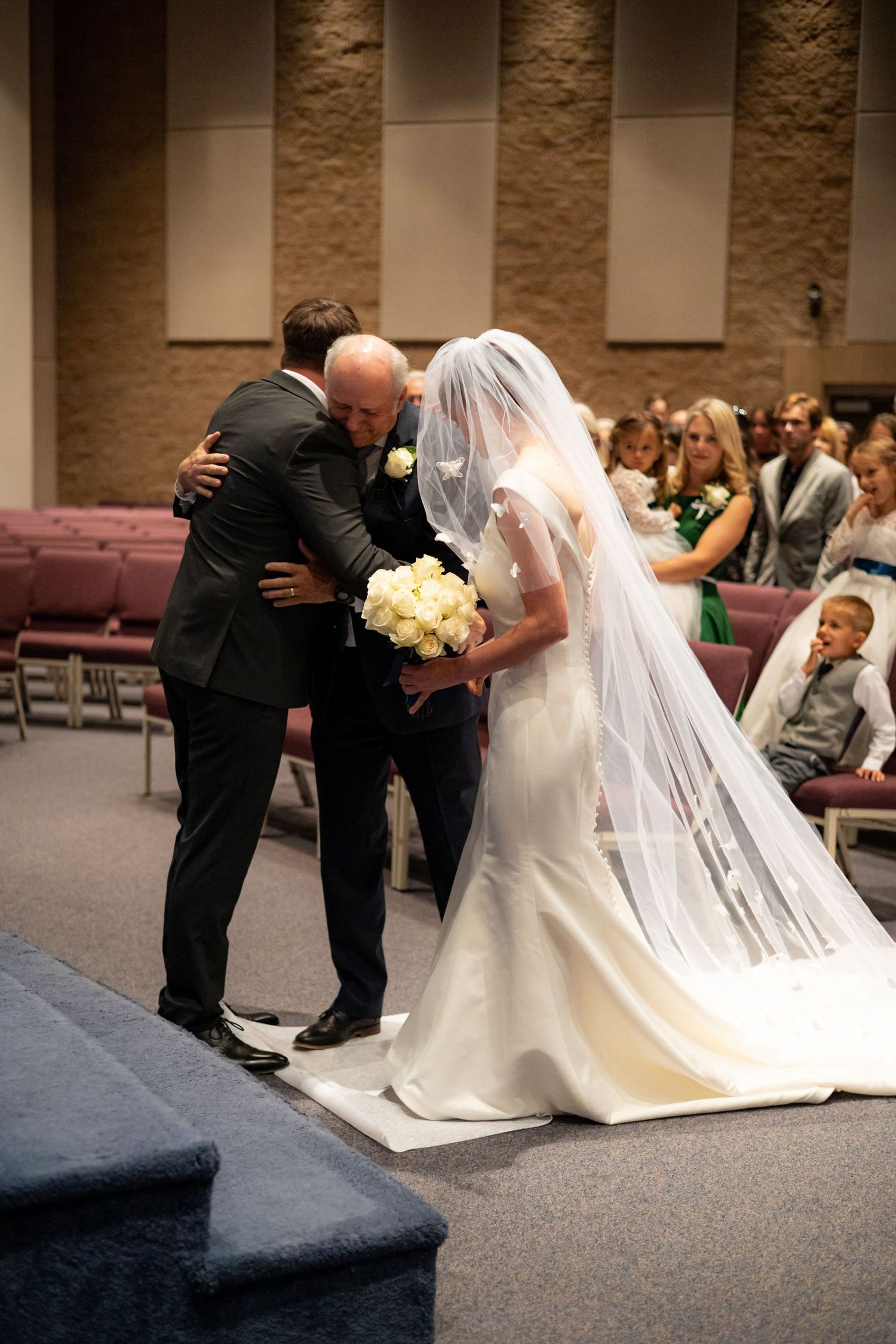 Emotional moment during a wedding ceremony as participants kneel at the altar.