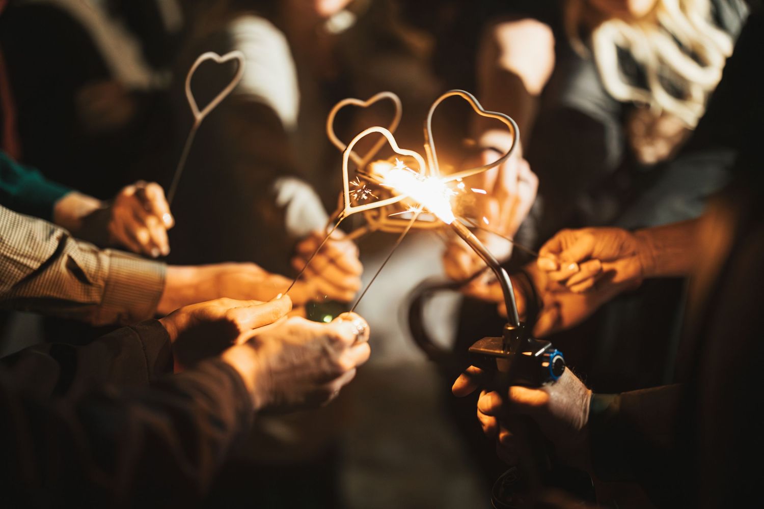 Heart-shaped sparklers glowing in the dark at wedding celebration.