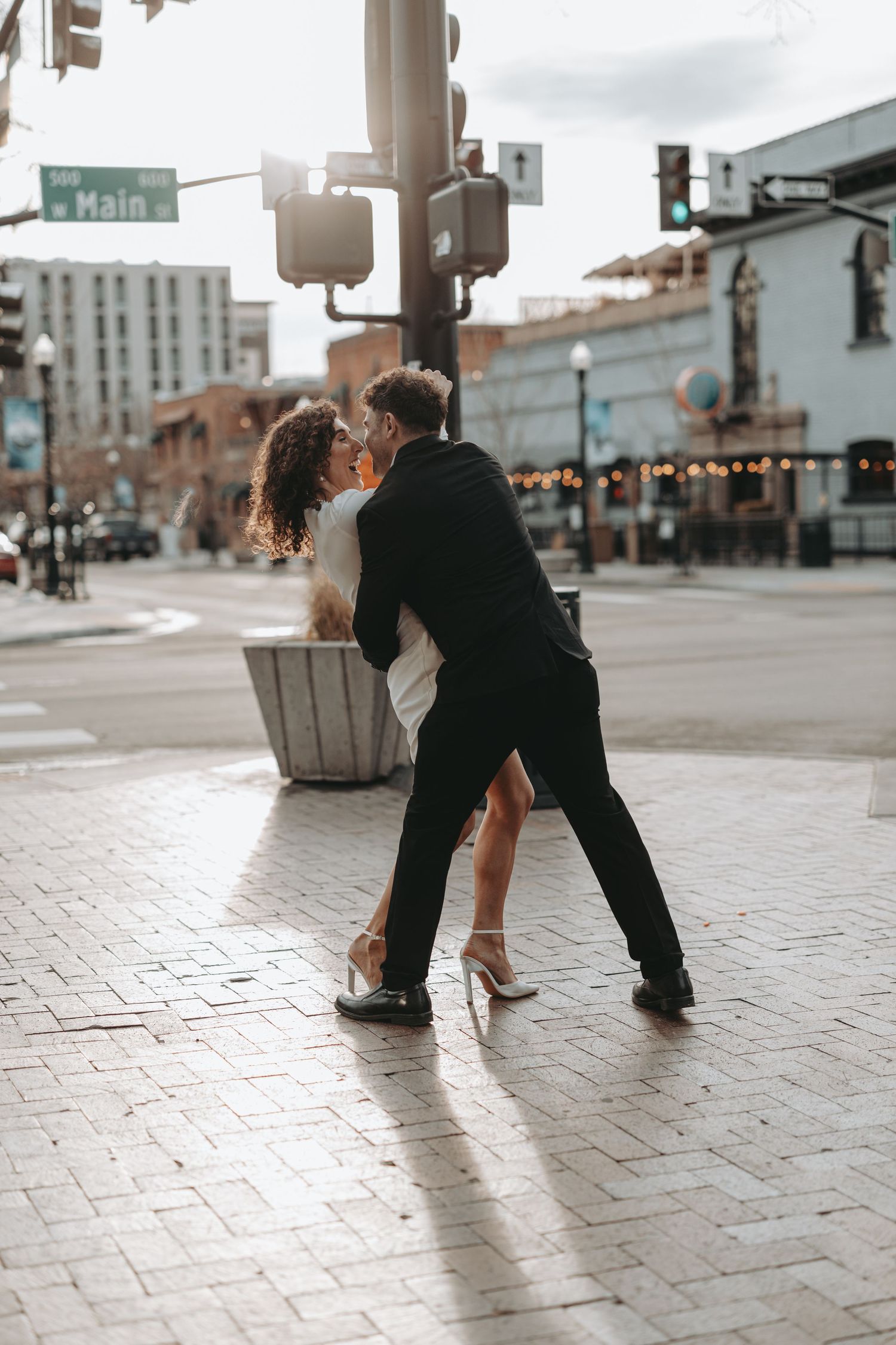 A couple dancing in a romantic dip pose on a city street with buildings in background.