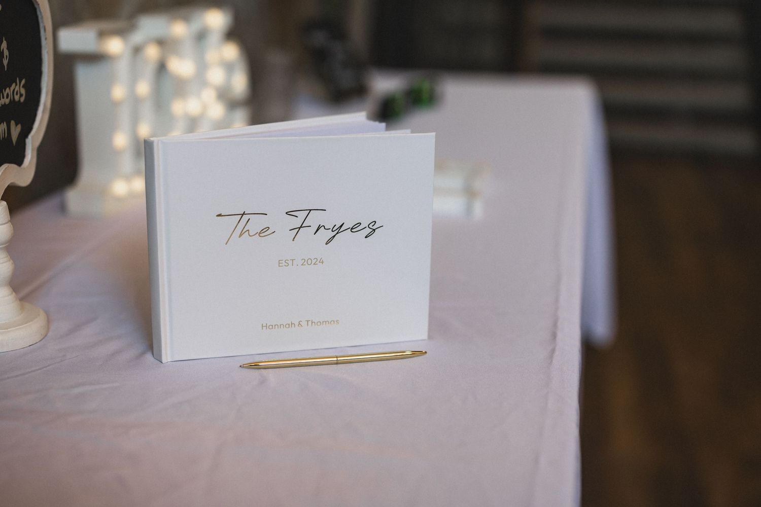 Wedding place card reading 'The Hopes' displayed on white linen tablecloth.