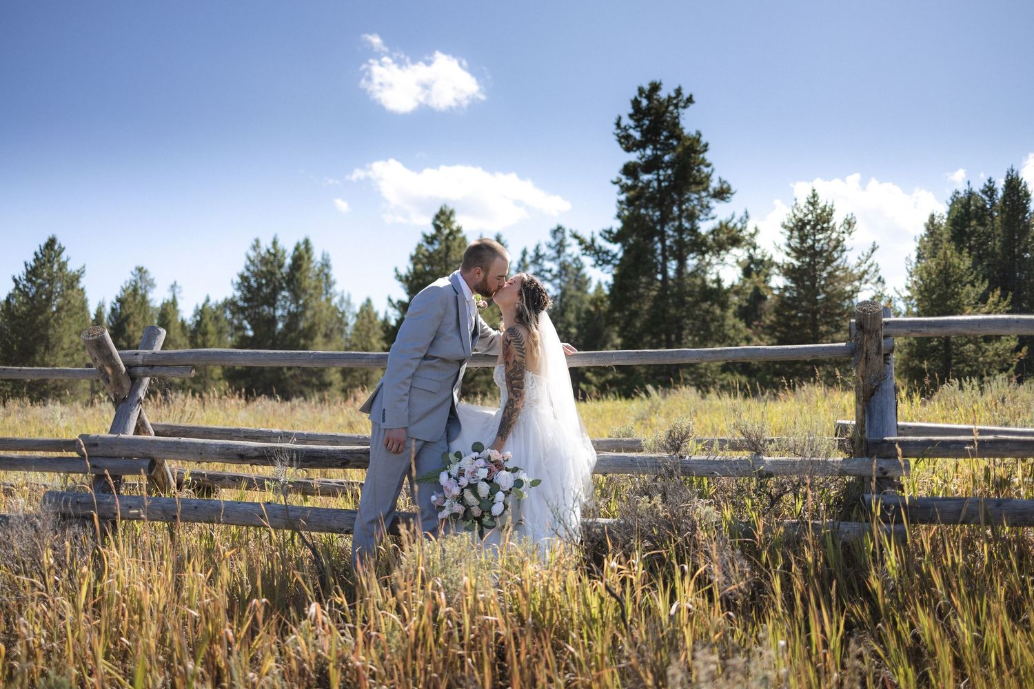 Wedding photos captured along a wooden split-rail fence against a mountain landscape.