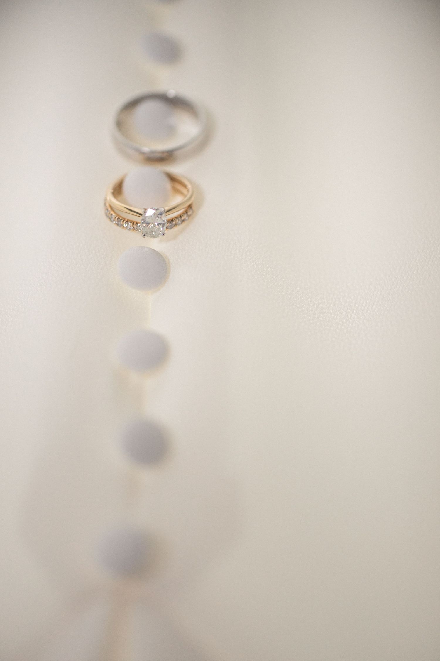 Close-up of elegant diamond engagement ring and wedding band on white surface.