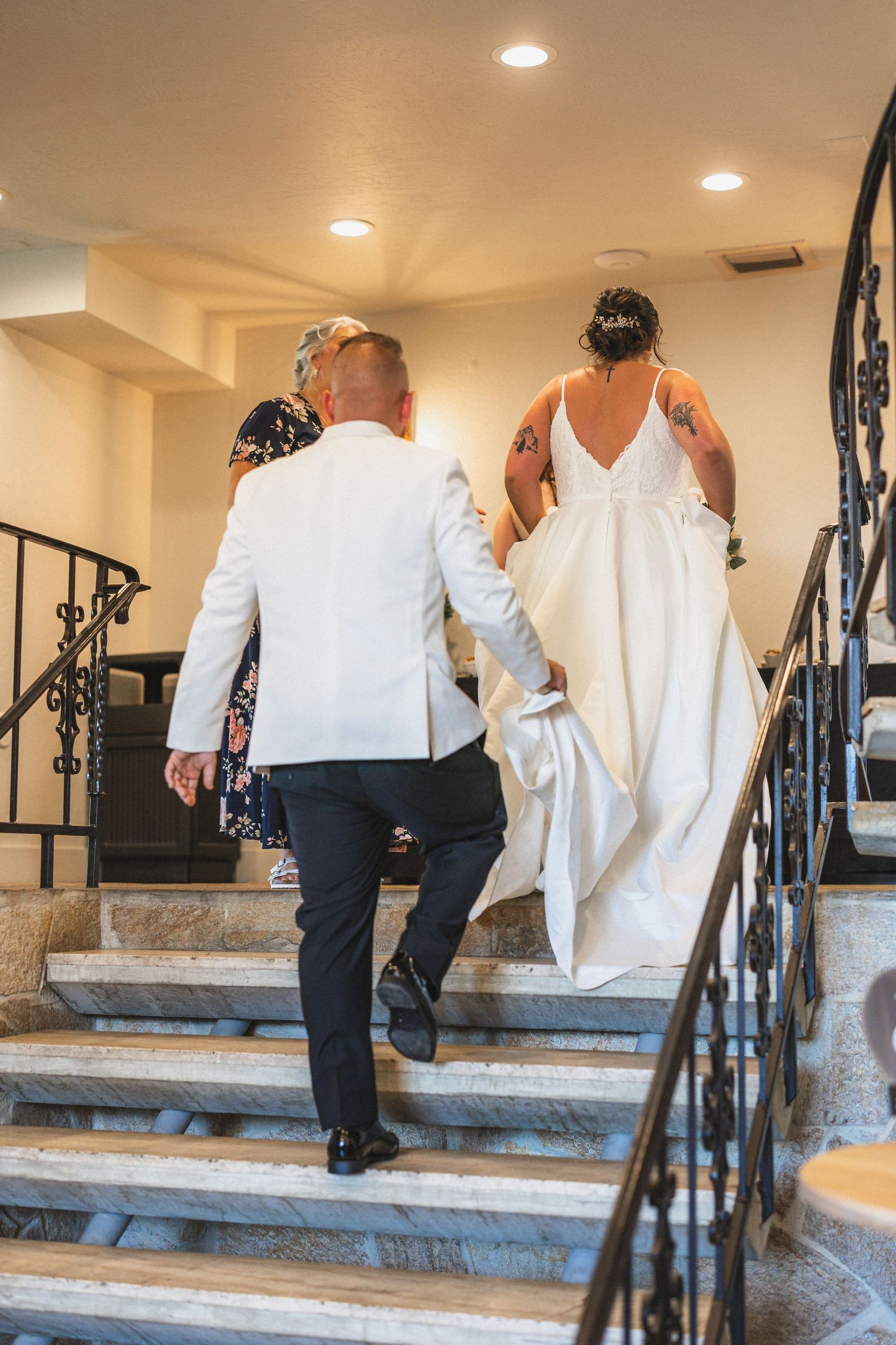 Couple ascending elegant indoor staircase with ornate railings after their wedding ceremony.