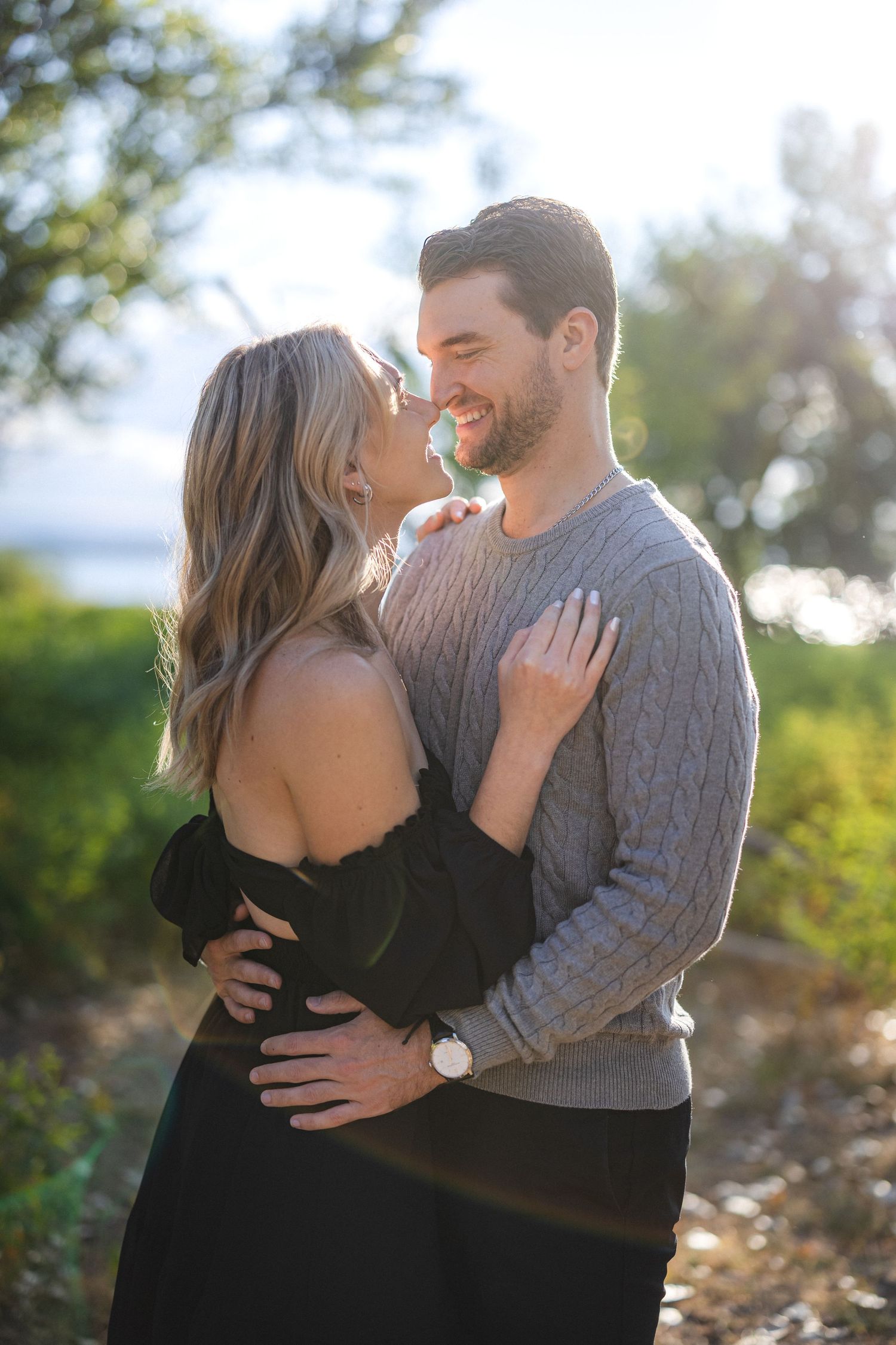 A romantic couple embracing outdoors during a sunset photoshoot.