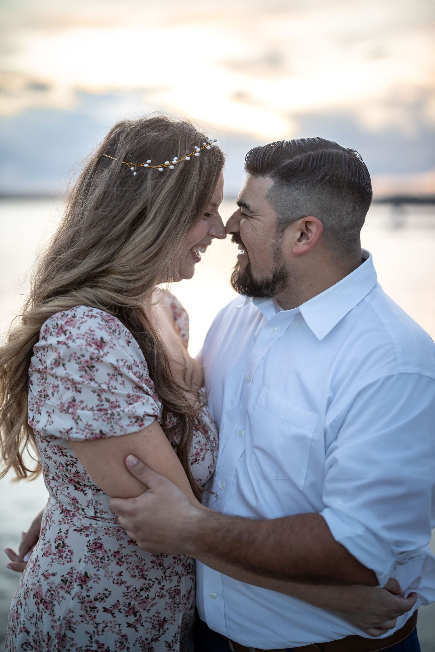 Intimate moment captured against serene waterfront backdrop.