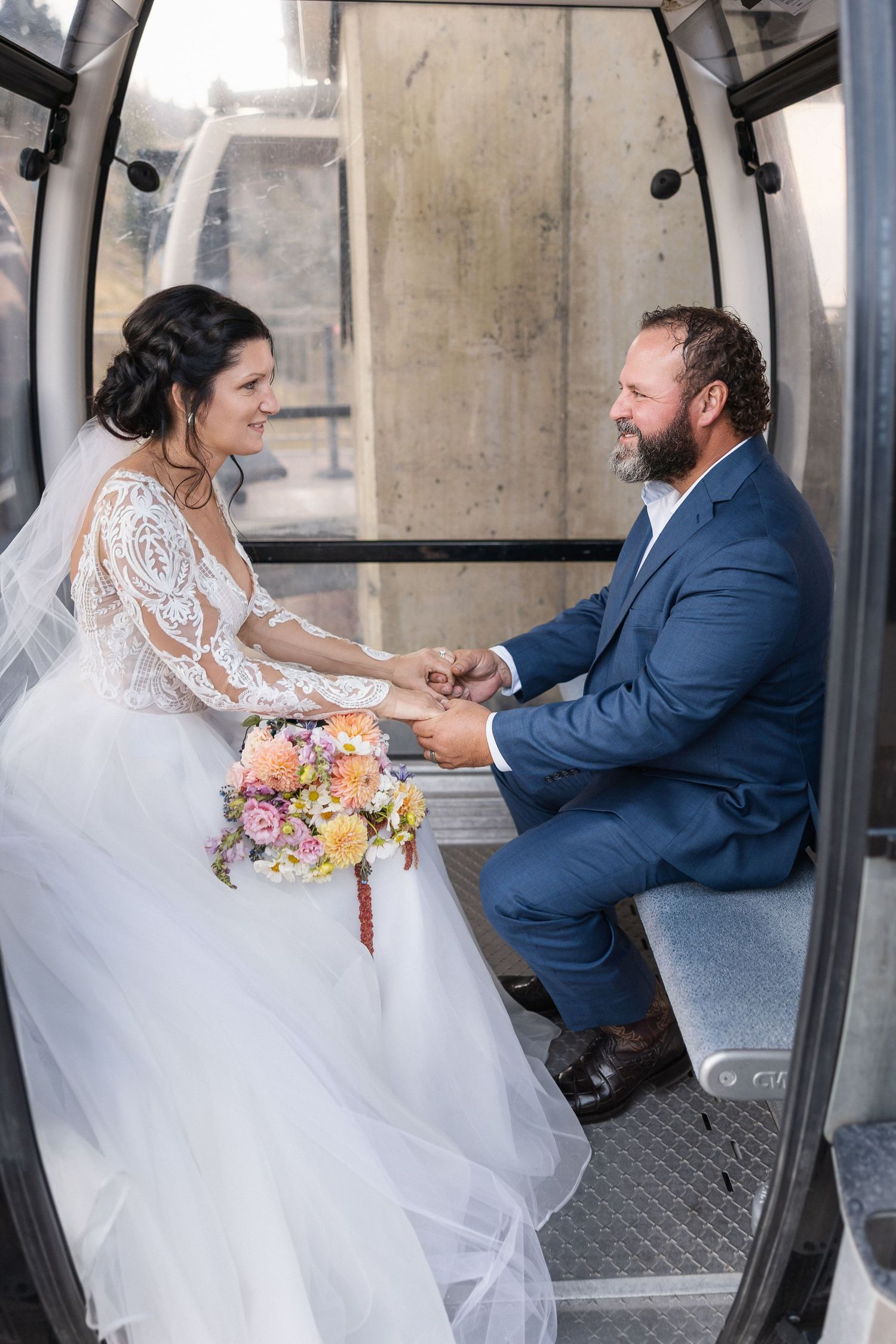 Wedding couple sharing a playful moment inside a gondola or cable car.