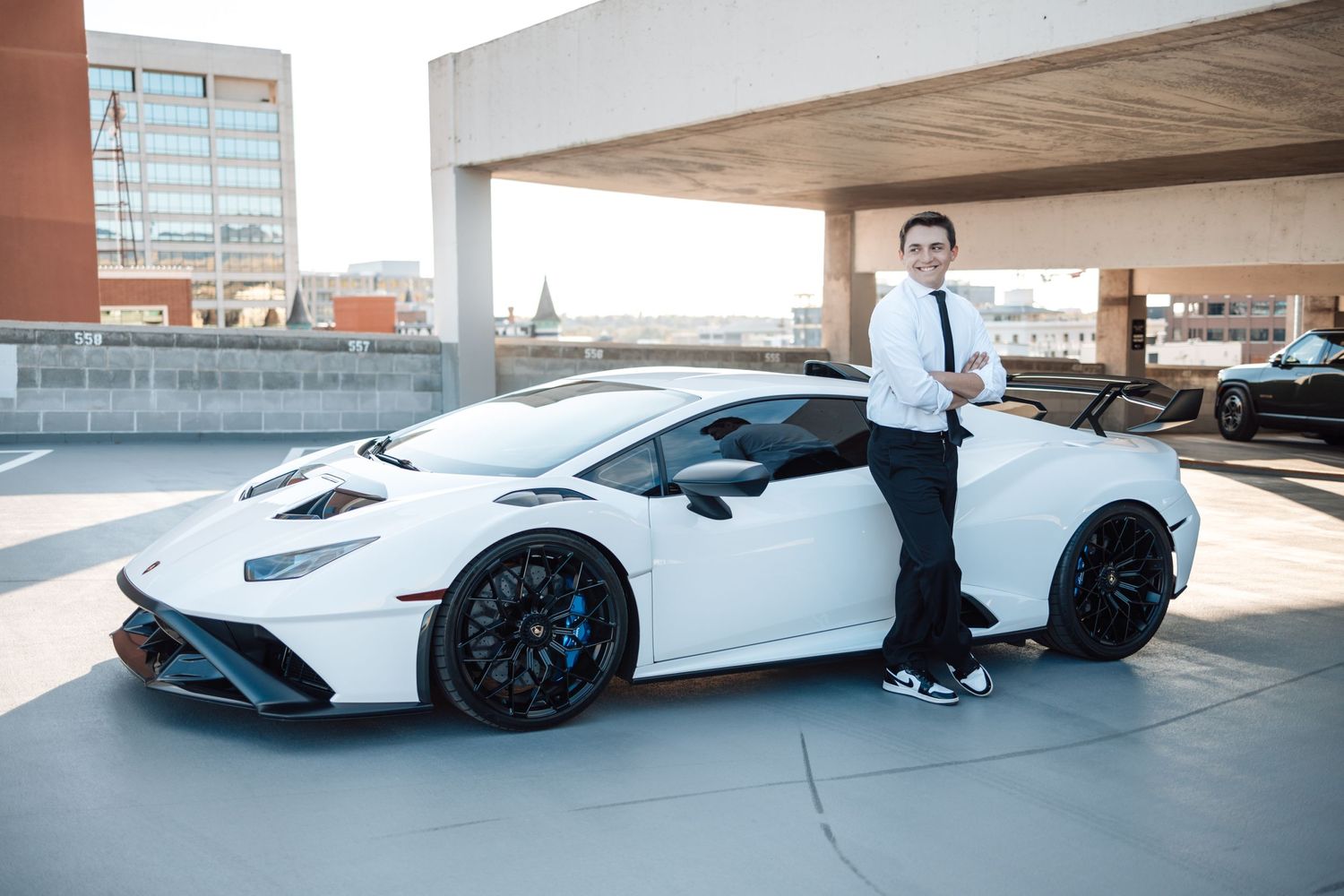 White Lamborghini Huracan with blue accents parked in urban parking garage setting.