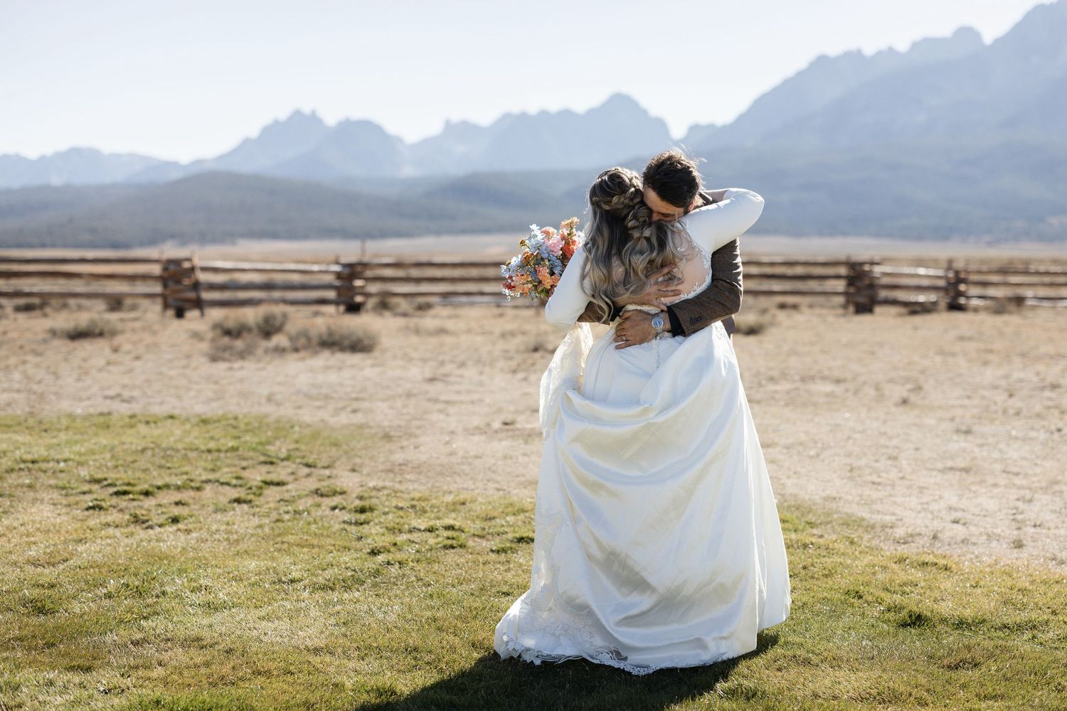 Wedding ceremony setup in an open field with mountain ranges in the distance.