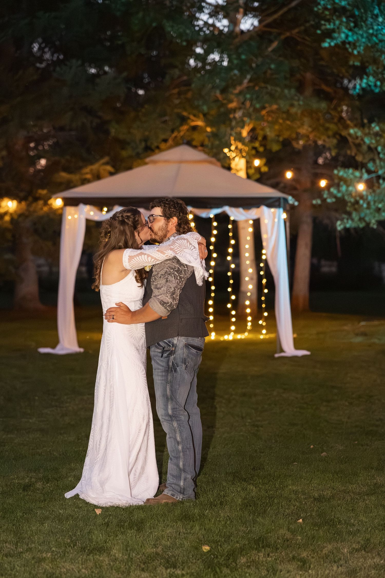 Romantic first dance under string lights and outdoor tent at dusk wedding reception.