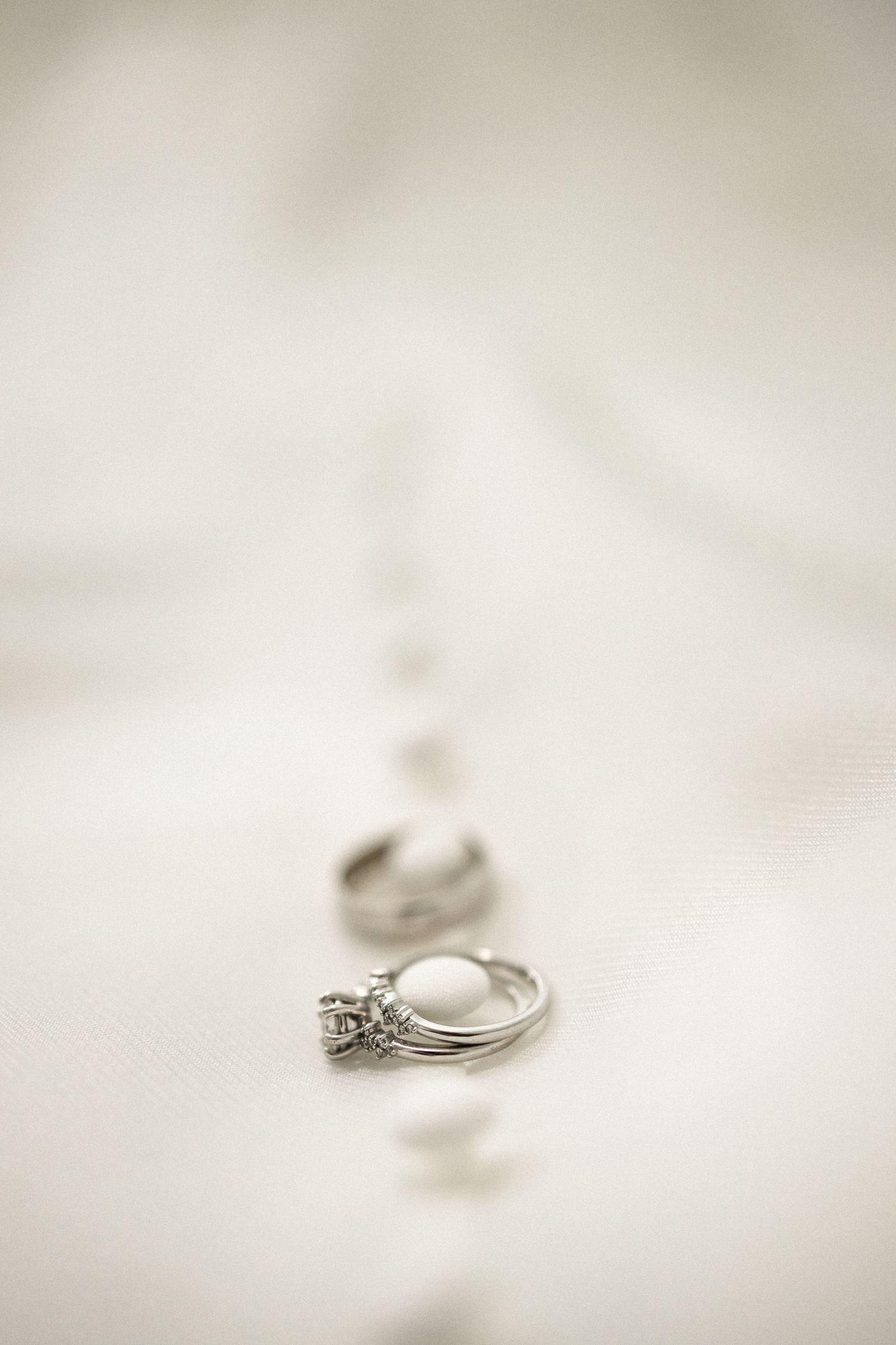 Close-up of wedding rings on white fabric with soft focus.
