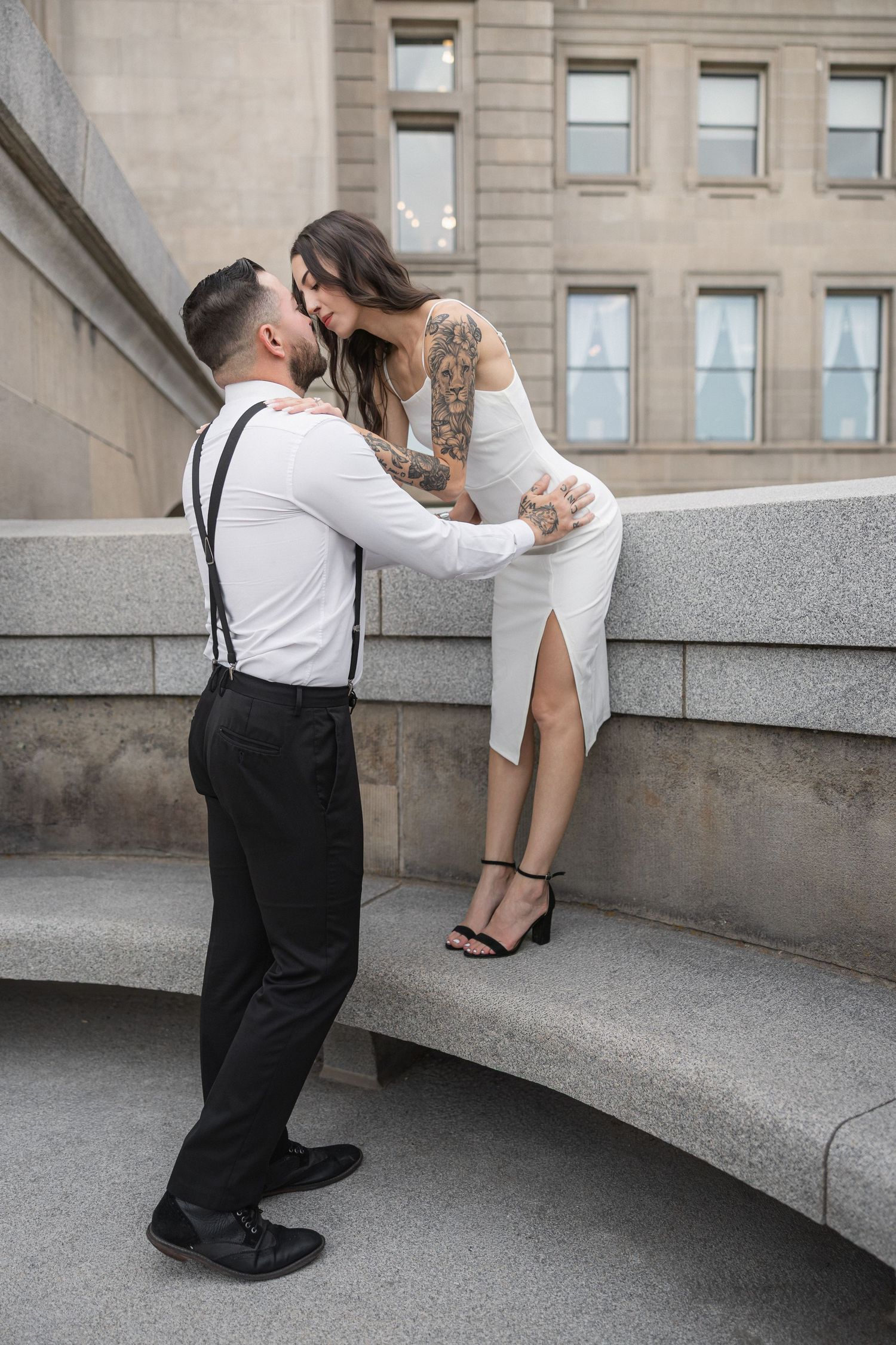 A romantic moment unfolds on curved stone steps of a government building.
