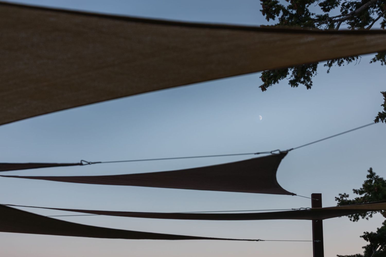White shade sails stretch across a blue sky providing outdoor event coverage.