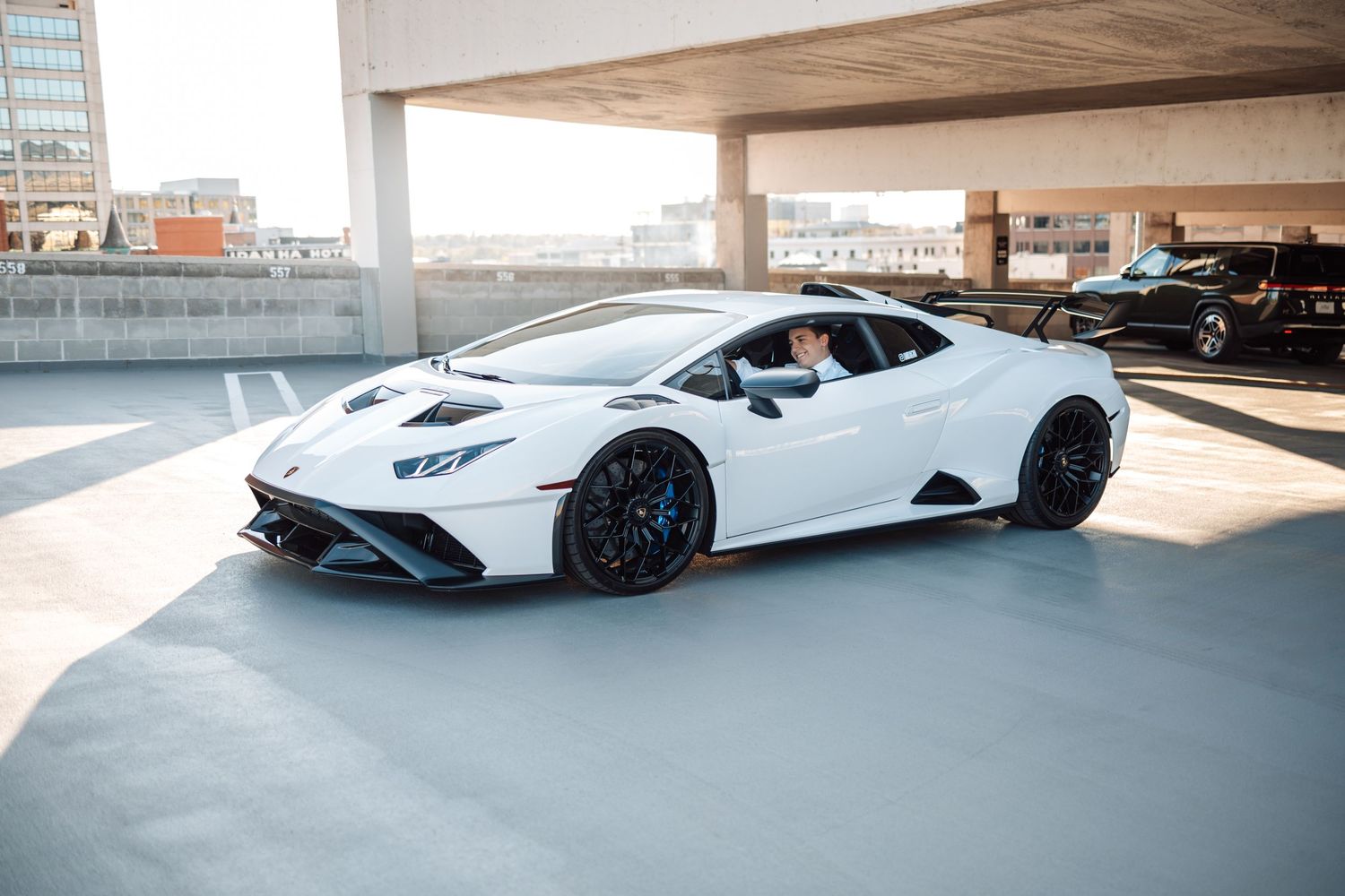 White Lamborghini Countach LPI 800-4 supercar parked in modern concrete parking structure with dramatic lighting.