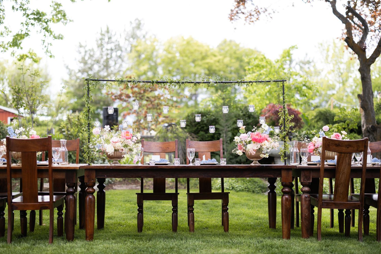 Long wooden farm tables set up outdoors for a rustic garden reception.