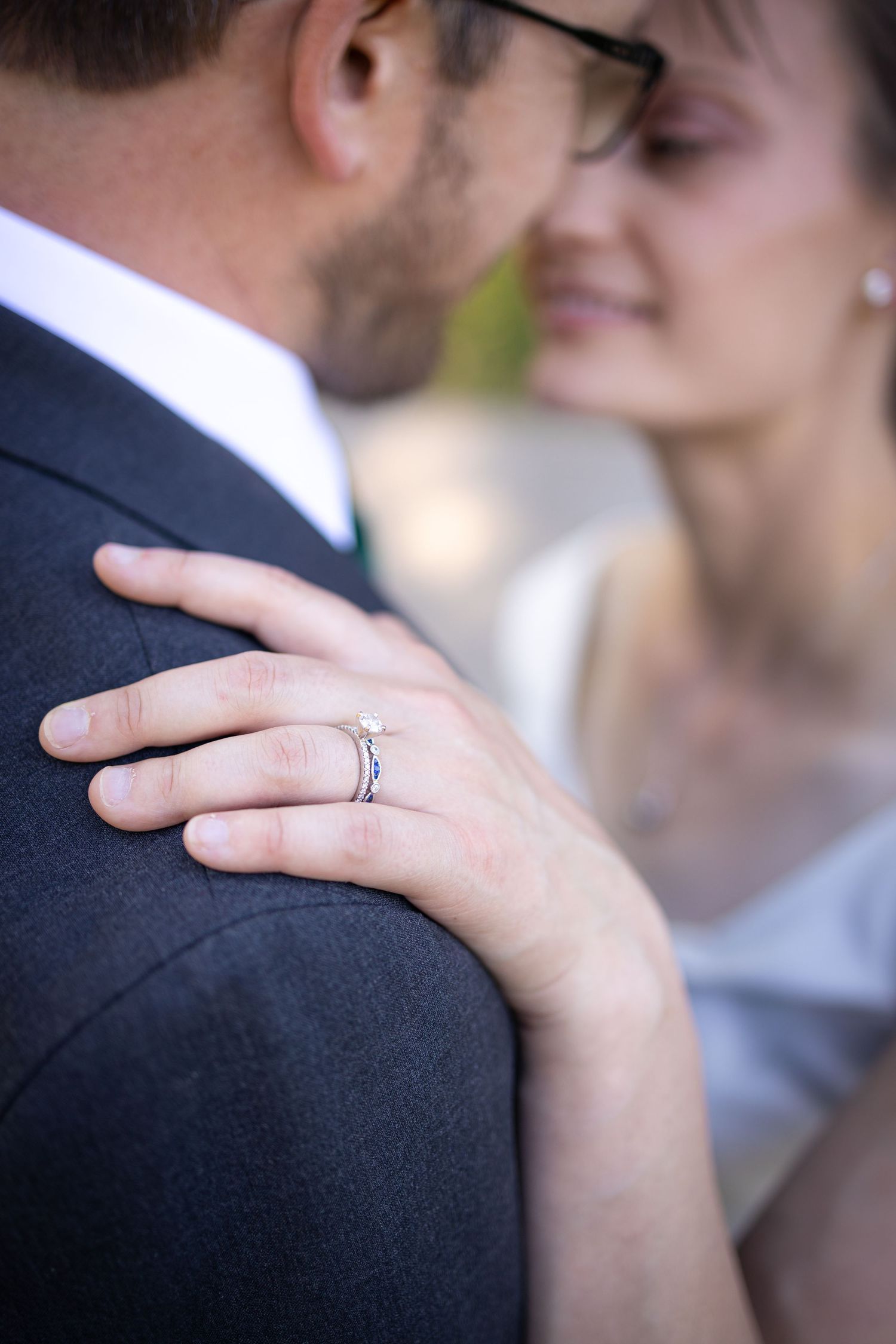 Close-up of wedding ring detail as couple shares intimate moment.