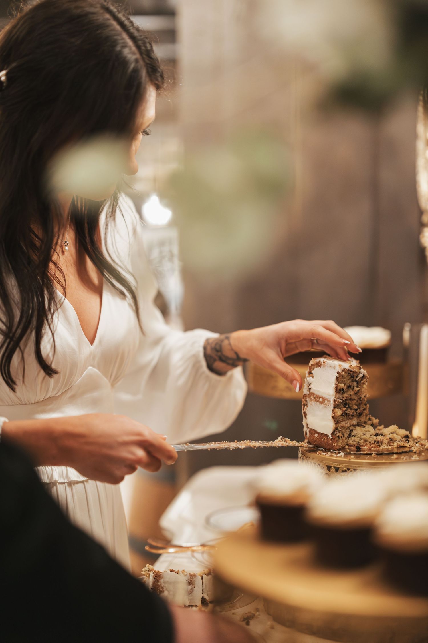Person in white dress serving desserts at rustic wedding reception.