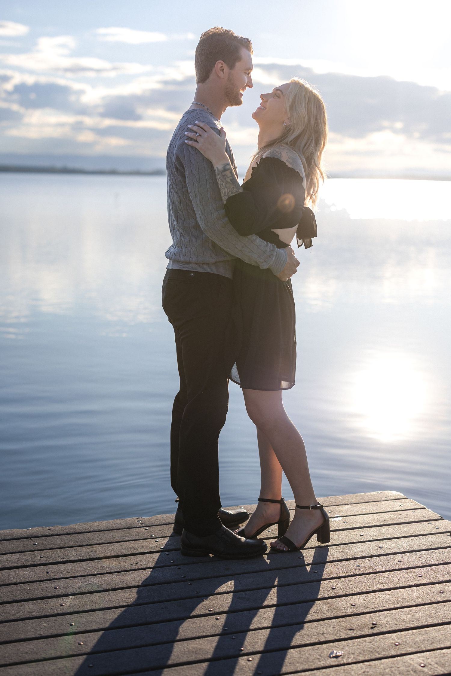Romantic moment between couple on waterfront dock during sunset.