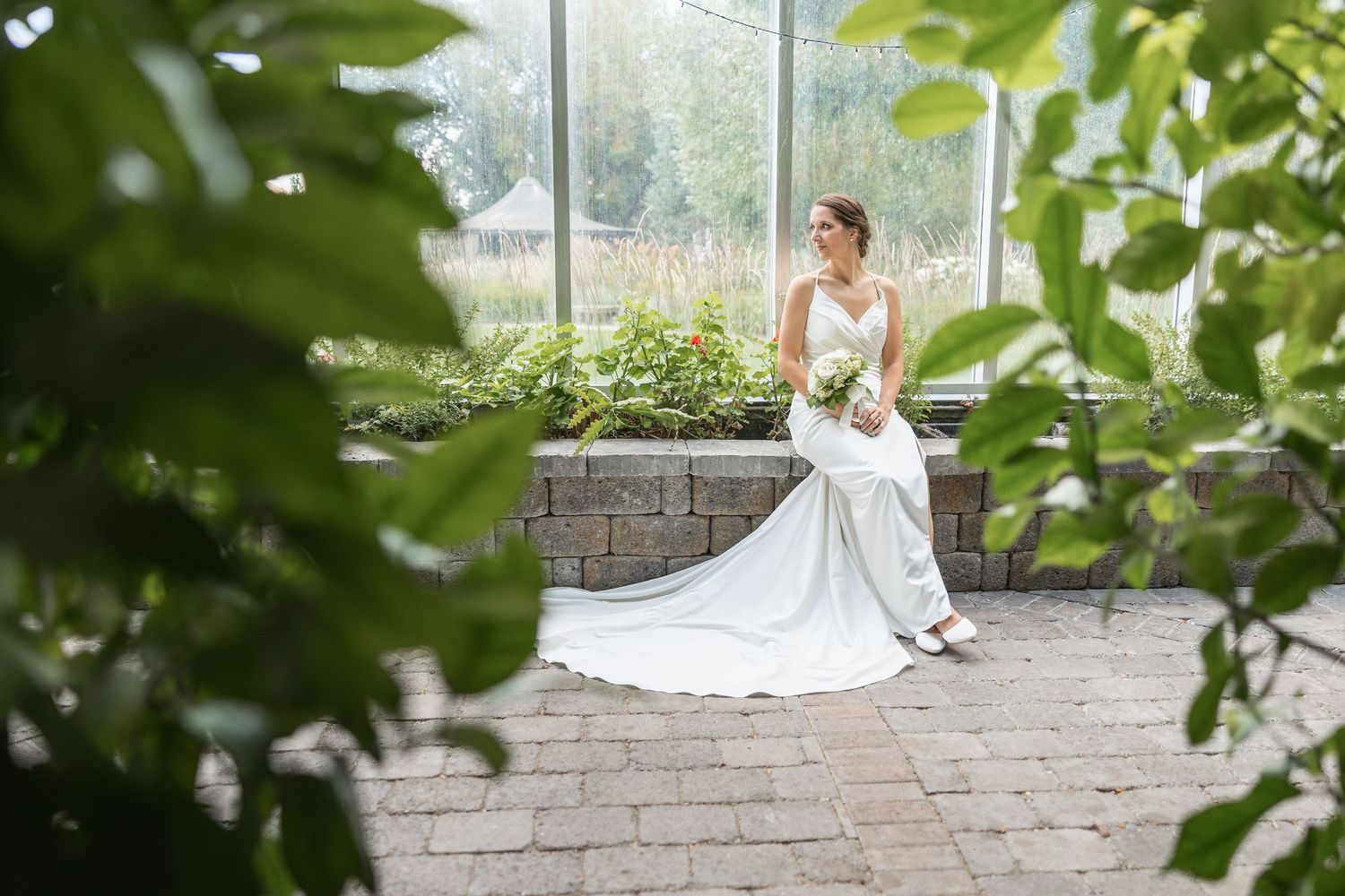 Elegant bridal portraits in a greenhouse garden setting with natural light filtering through.