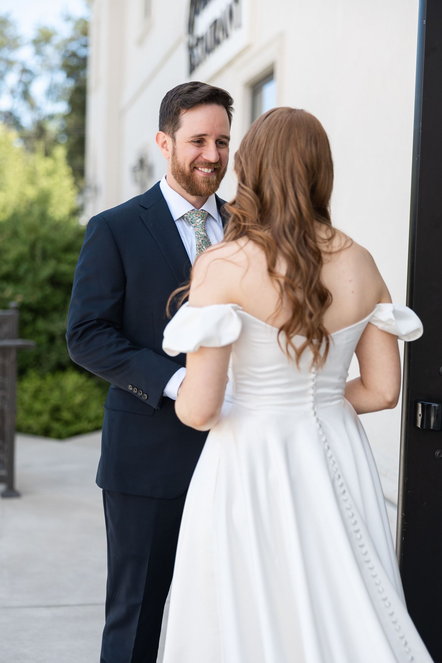 Bride in white dress and groom in navy suit share intimate first look photos.