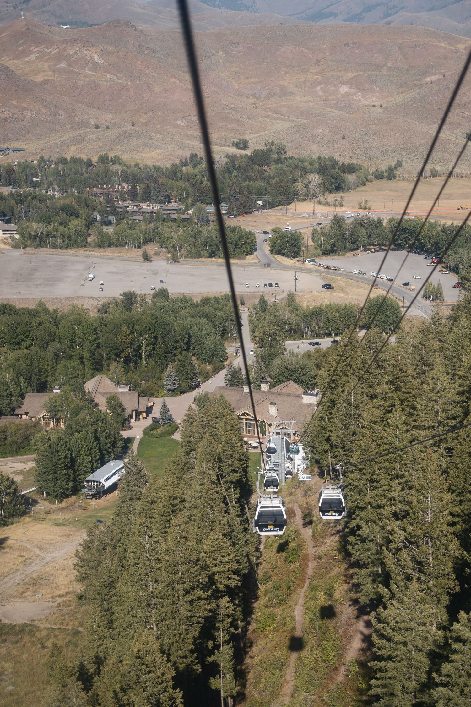Aerial view of ski resort gondolas traversing over pine-covered mountain terrain.