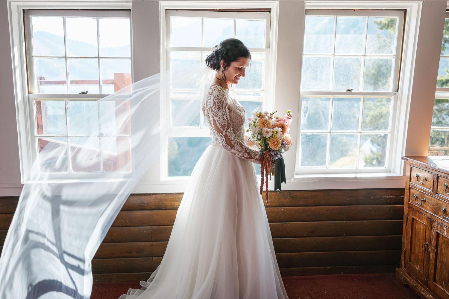 Sunlit wedding venue interior with wooden pews and large windows.