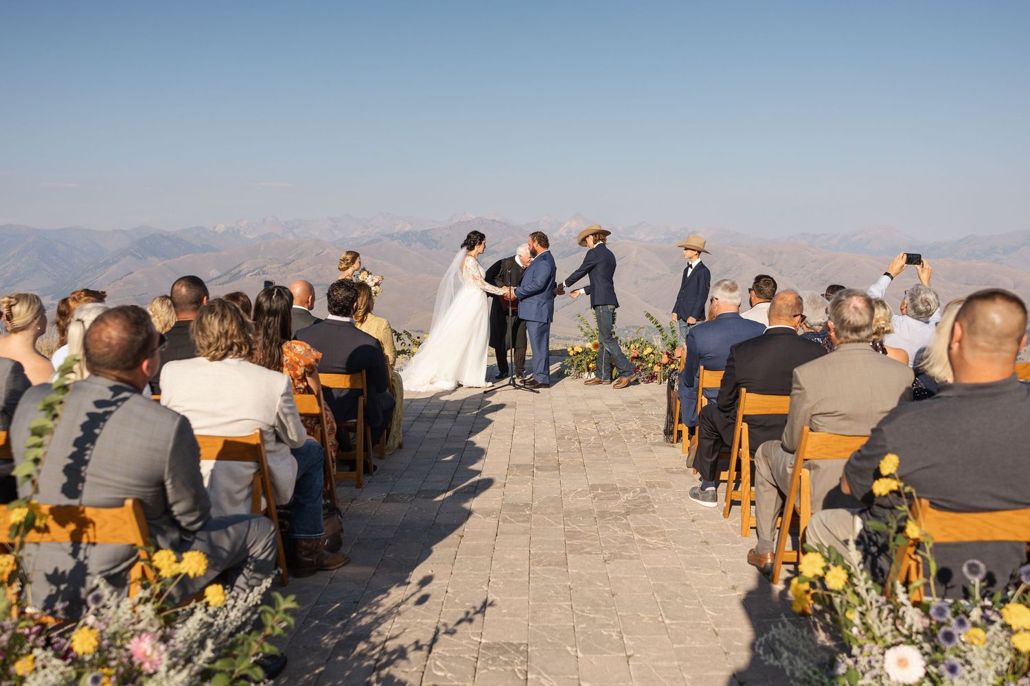 Outdoor wedding ceremony setup with wooden chairs overlooking mountain vistas.