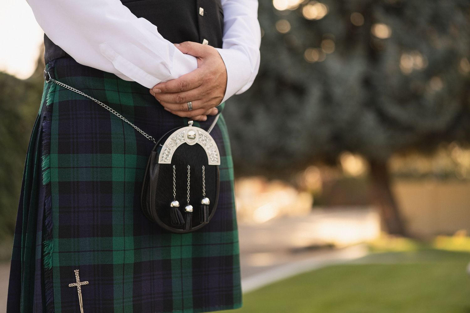 Detail shot of traditional Scottish kilt sporran in green and navy tartan pattern.
