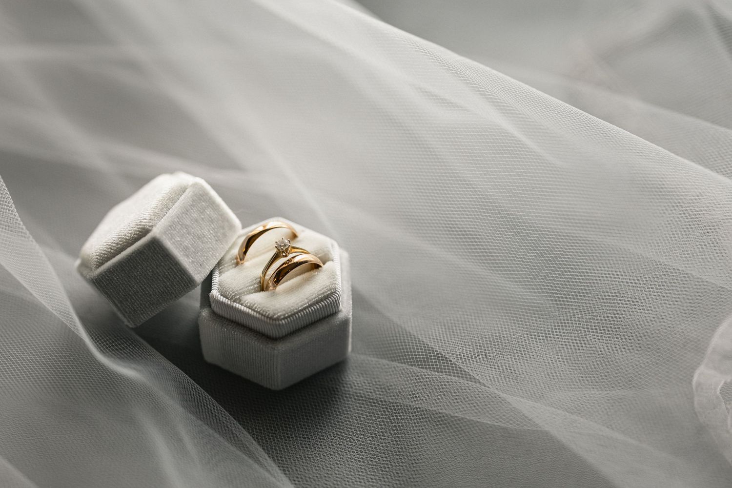 Wedding rings in hexagonal velvet box with delicate tulle fabric.