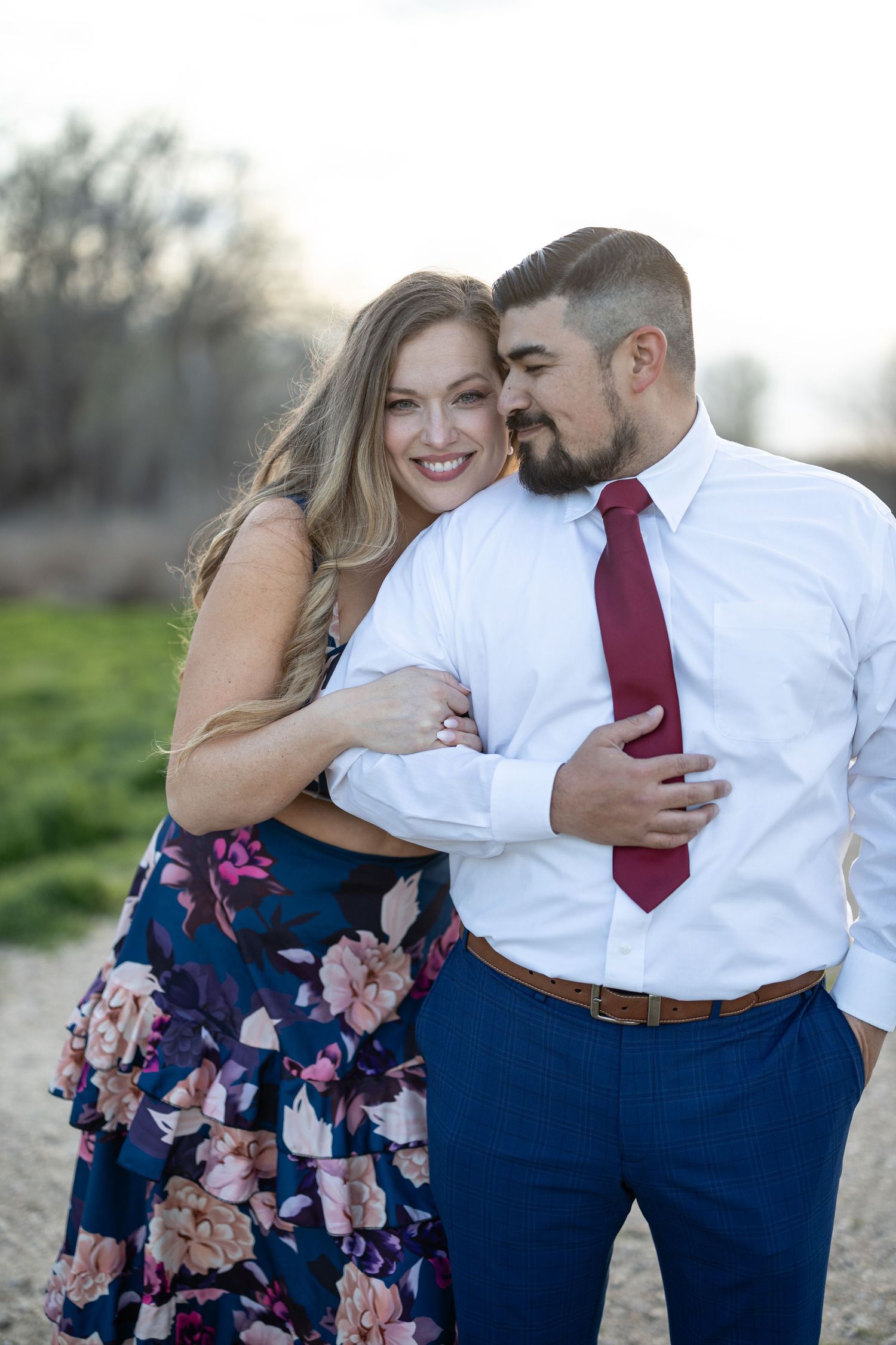 Intimate moment shared between a couple in formal wear on a rural path.