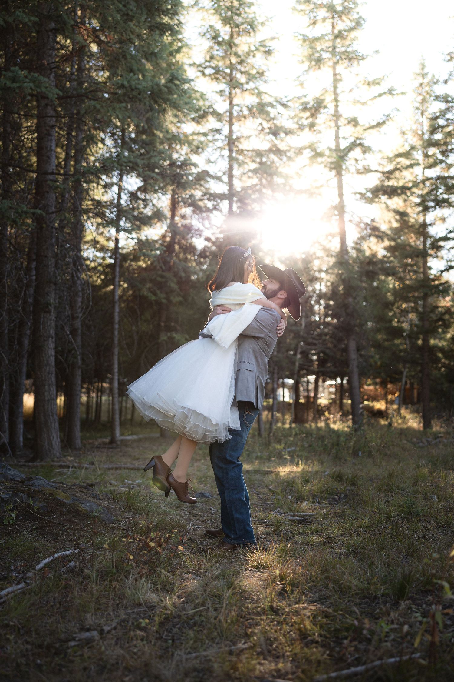 A romantic wedding moment captured in a forest as a couple embraces during golden hour.