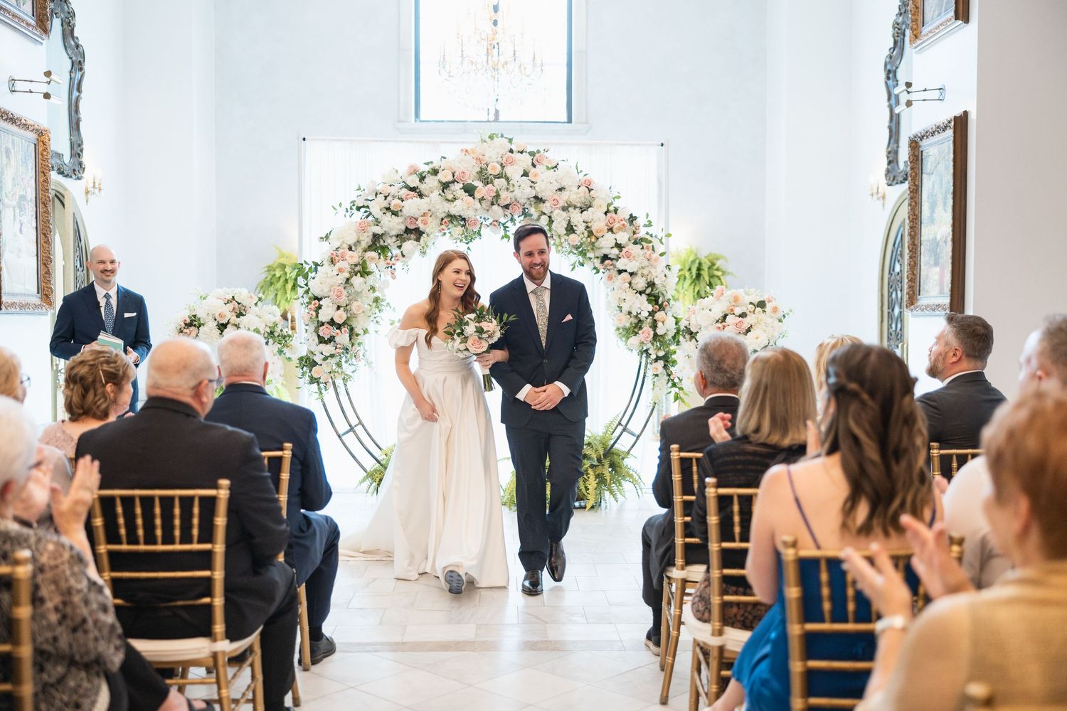 Indoor wedding ceremony space with white chairs and floral decorations in an elegant venue.
