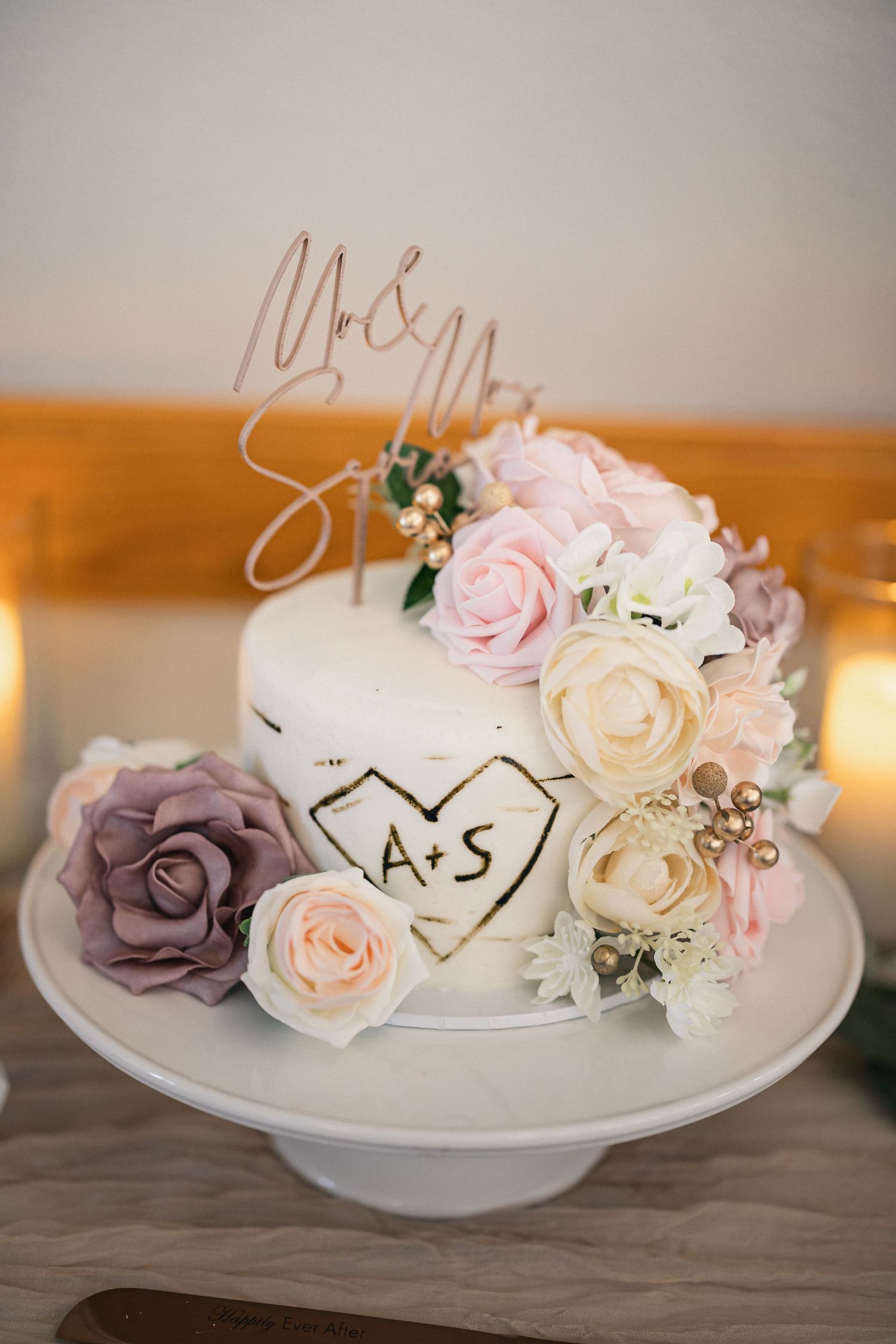 Elegant white wedding cake decorated with pink and mauve roses and a 'Mr & Mrs' topper.