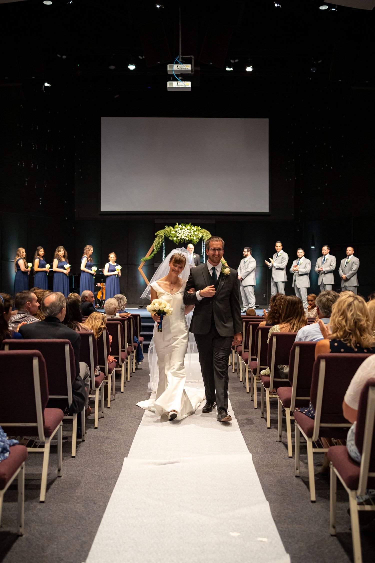 Full view of wedding ceremony venue with white aisle runner and geometric floral arch.