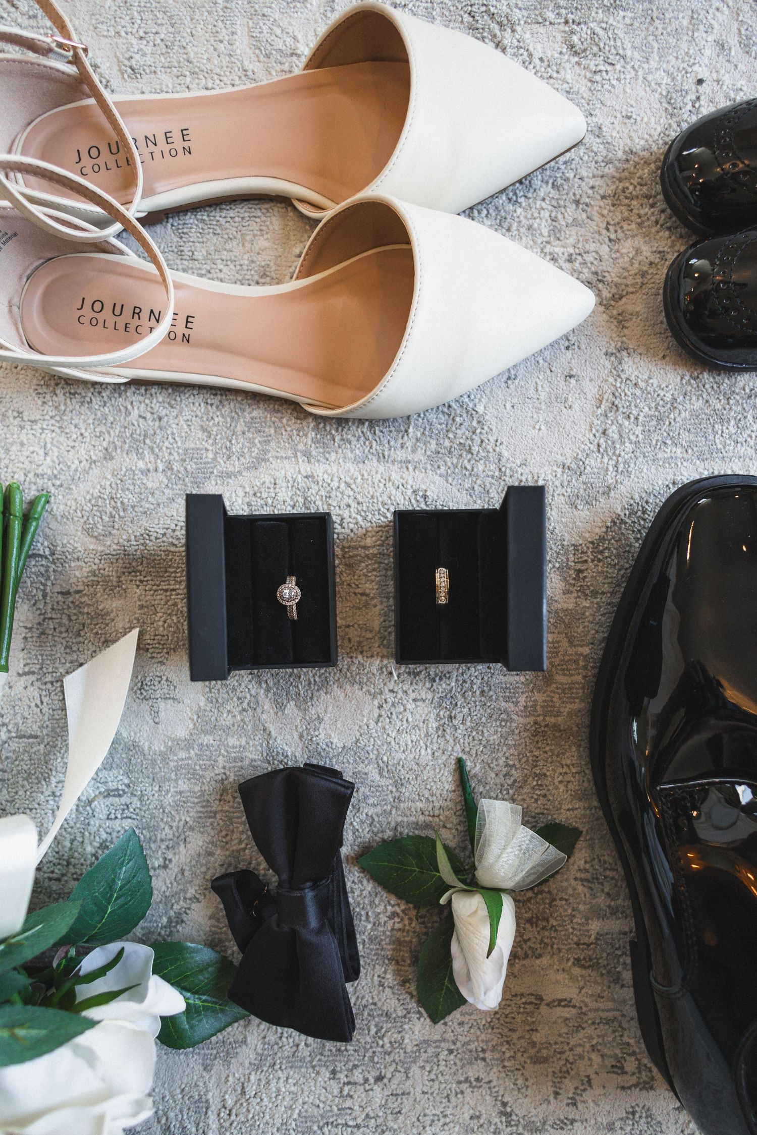 Wedding accessories including white bridal shoes, ring boxes and floral decorations.