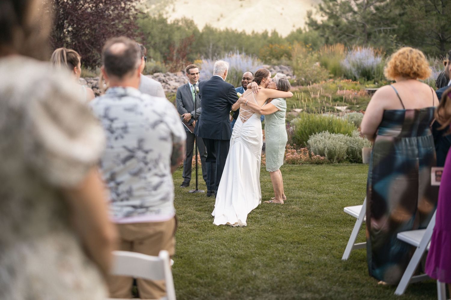 Wedding guests mingle on lawn during outdoor mountain reception.