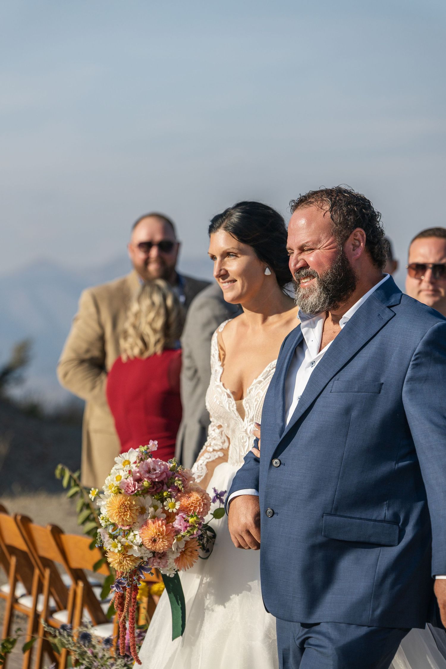 Wedding party standing on a stone patio with scenic mountain views during sunset.