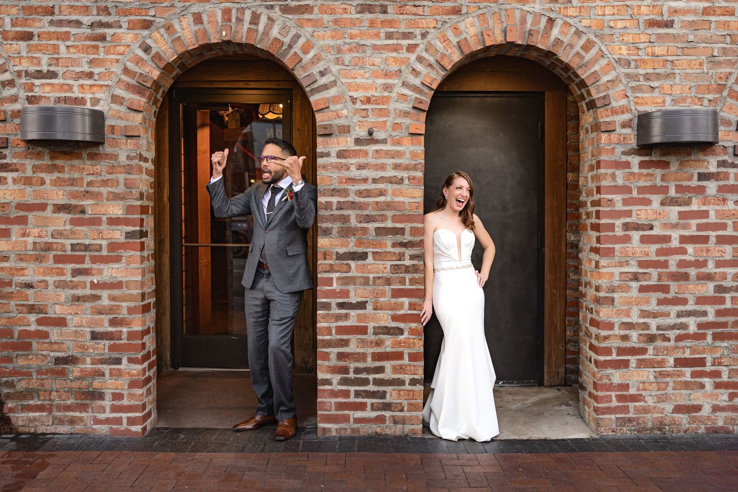 Bride and groom strike playful poses in separate brick doorways.