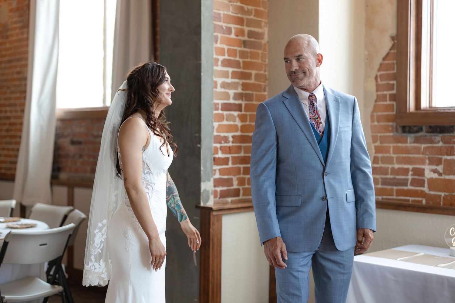 Emotional first look between couple in wedding dress and light blue suit.
