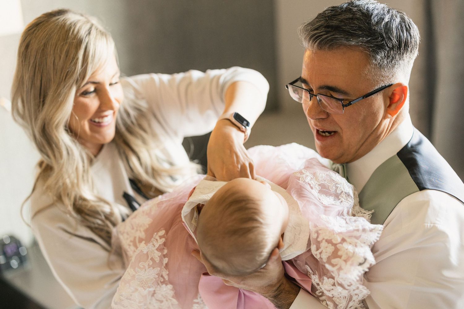 Tender moment during wedding preparations with infant in pink dress.