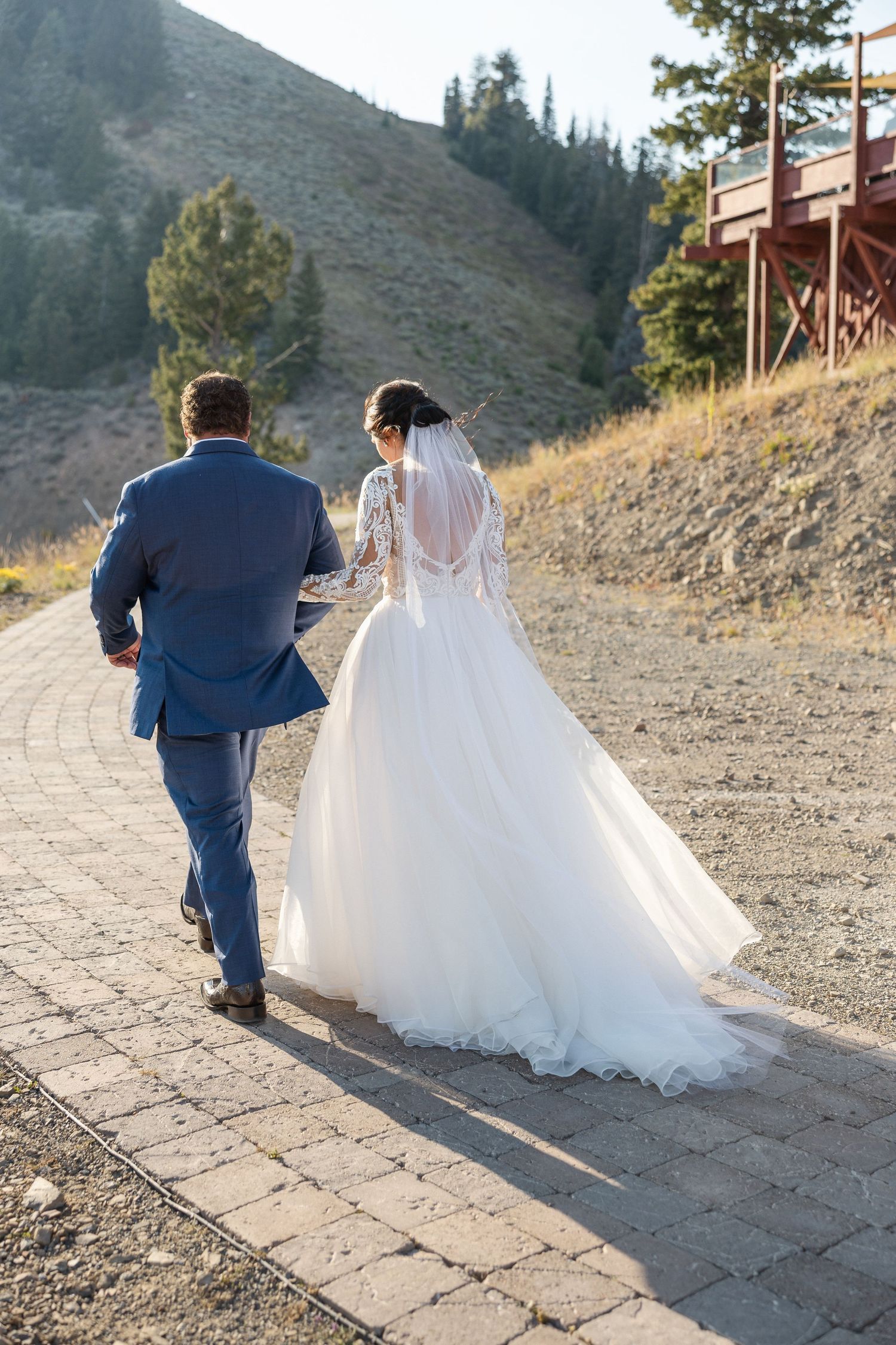 Couple walking down a stone pathway with mountain scenery in the background.
