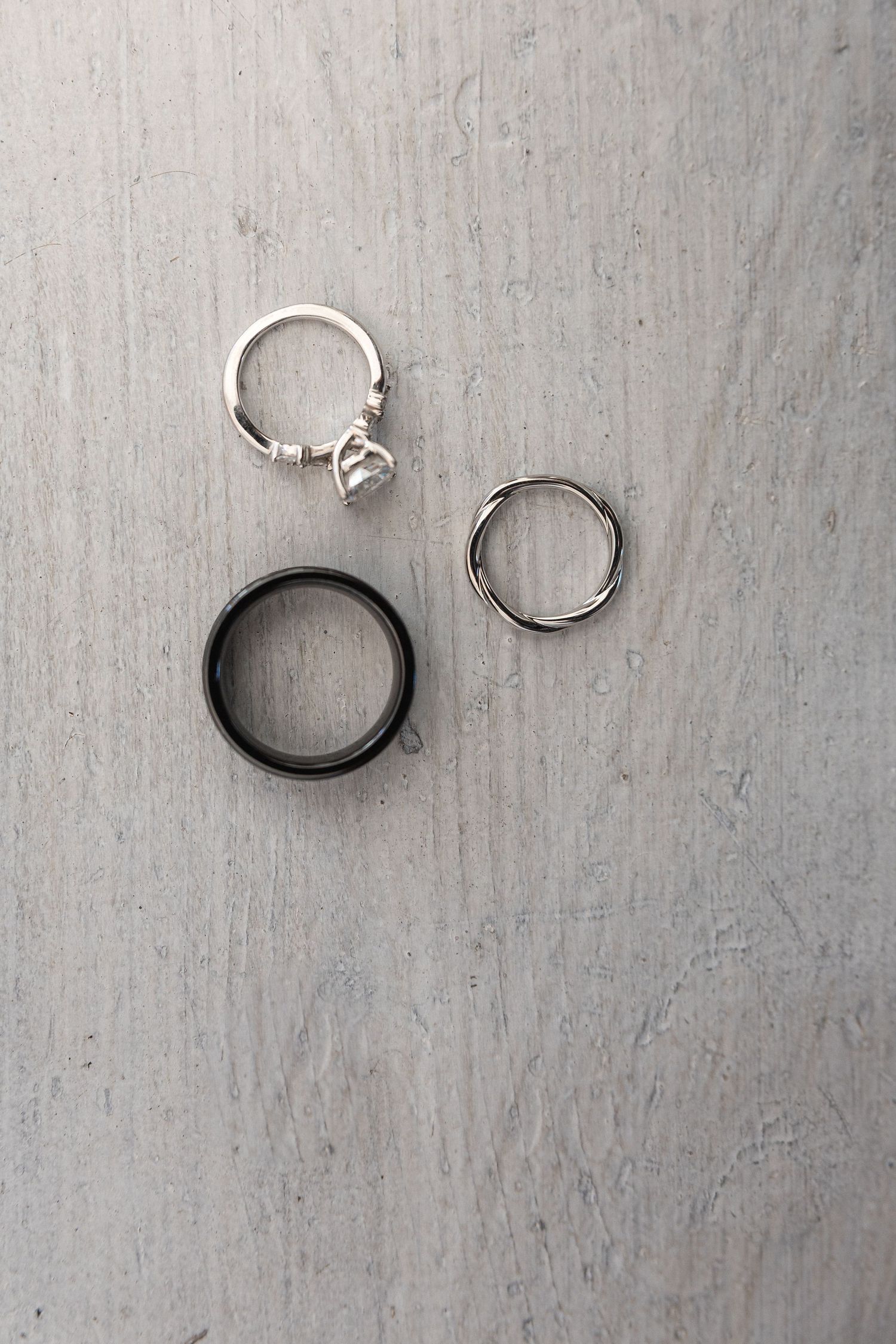 Three rings arranged on a gray textured surface, including one with a crystal charm.
