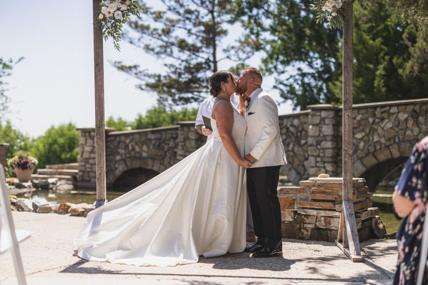 A wedding couple sharing an intimate moment outdoors by a stone structure.