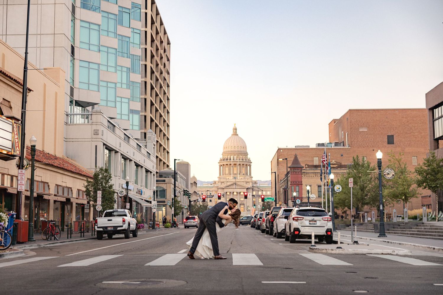 Urban street scene with Idaho State Capitol dome visible down a city avenue lined with buildings.