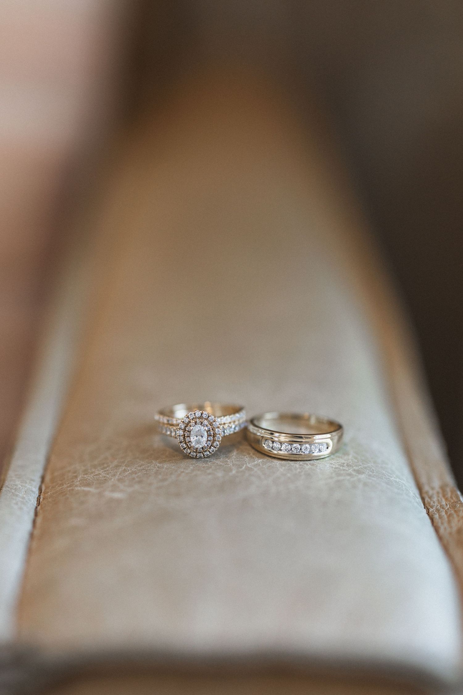 Two diamond wedding rings photographed in soft focus on a light beige surface.