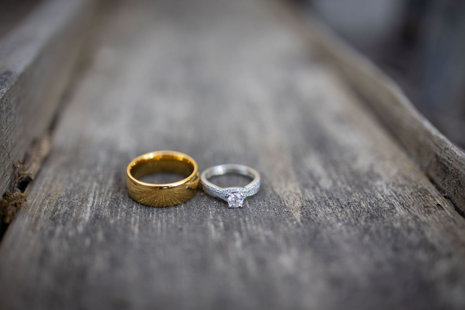 Gold and silver wedding rings displayed on weathered wooden surface.
