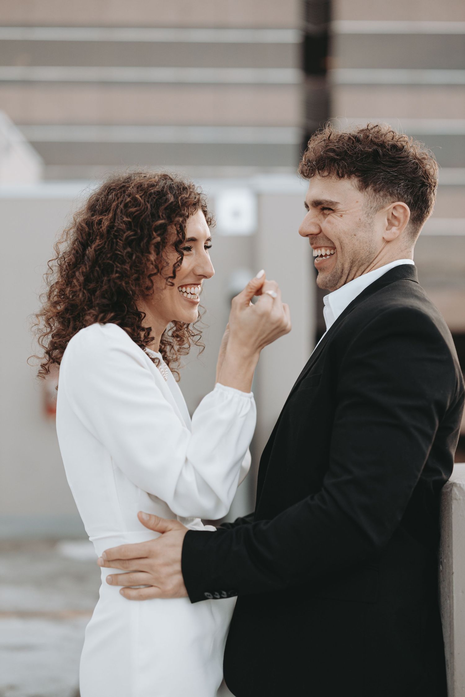 A romantic couple shares a playful moment together, with the woman in white and man in black enjoying a candid laugh.