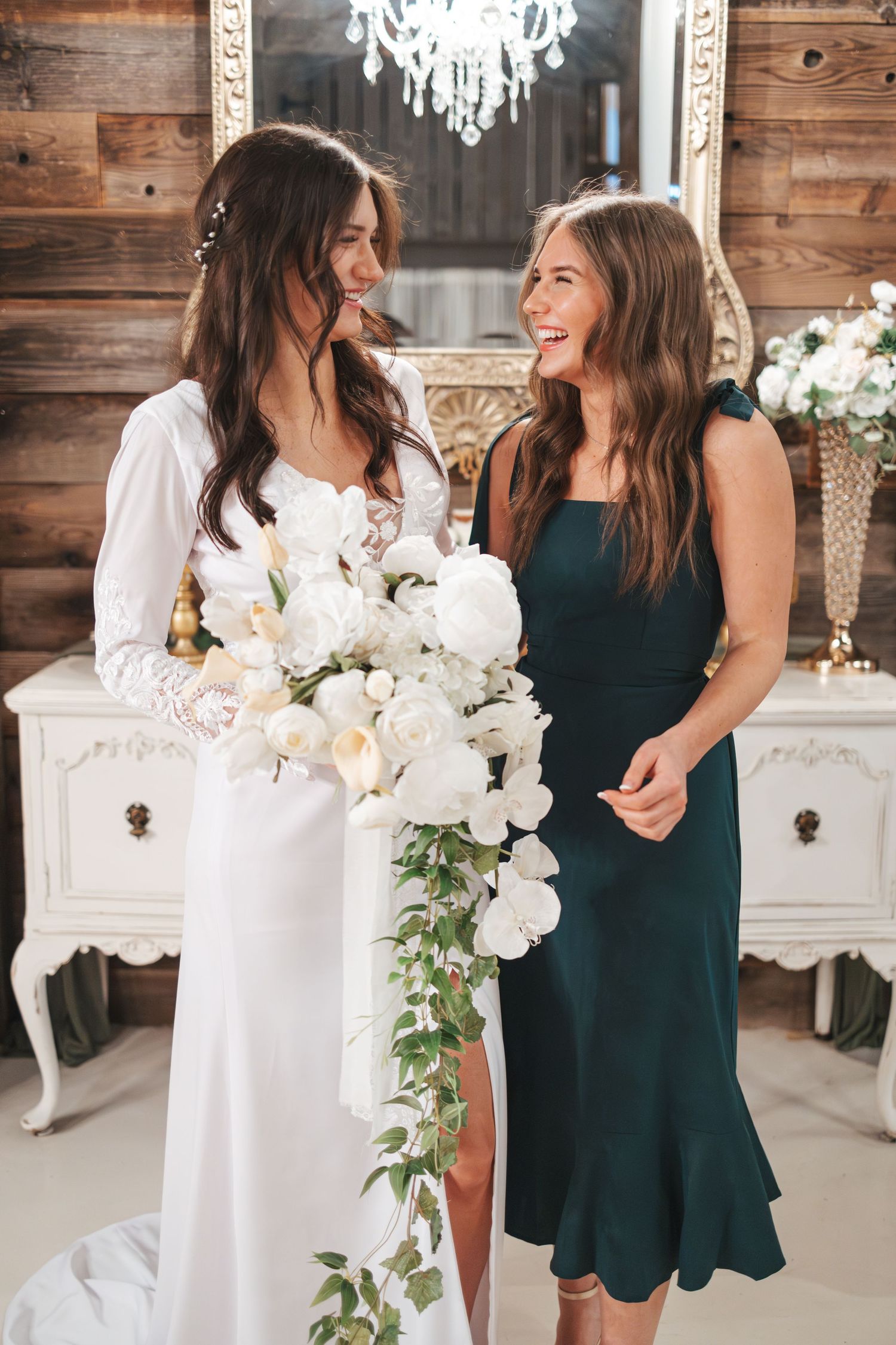 Wedding setting featuring elegant white dresser with crystal chandelier and floral decorations.