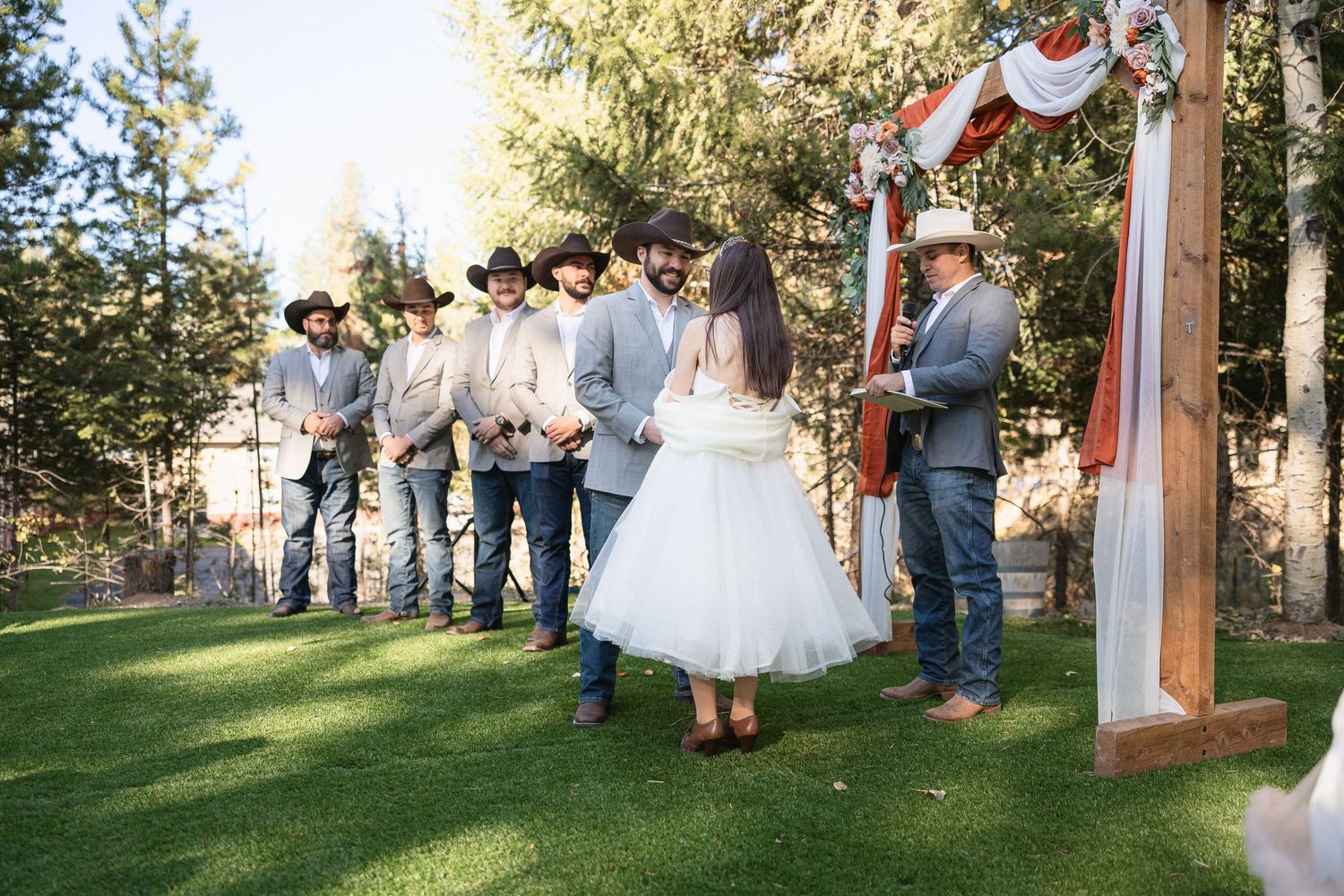 Wedding celebration scene with guests gathered under string lights at outdoor venue.