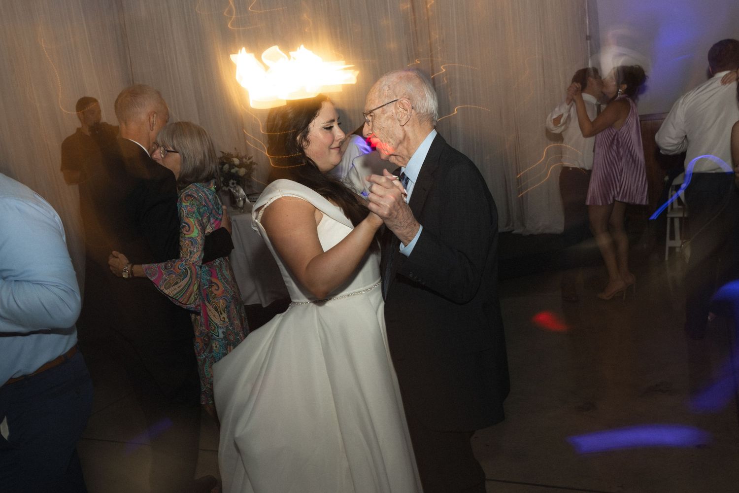 A sweet moment between dancers on the wedding reception dance floor with moody lighting.